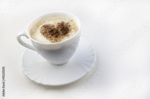 A cup of coffee on a white background a heart made from cinnamon