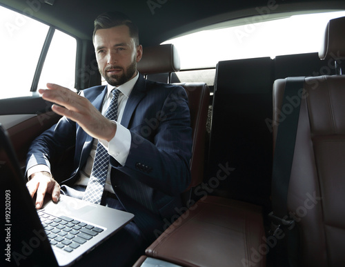 businessman sitting in the back seat in the car and pointing his finger forward © ASDF