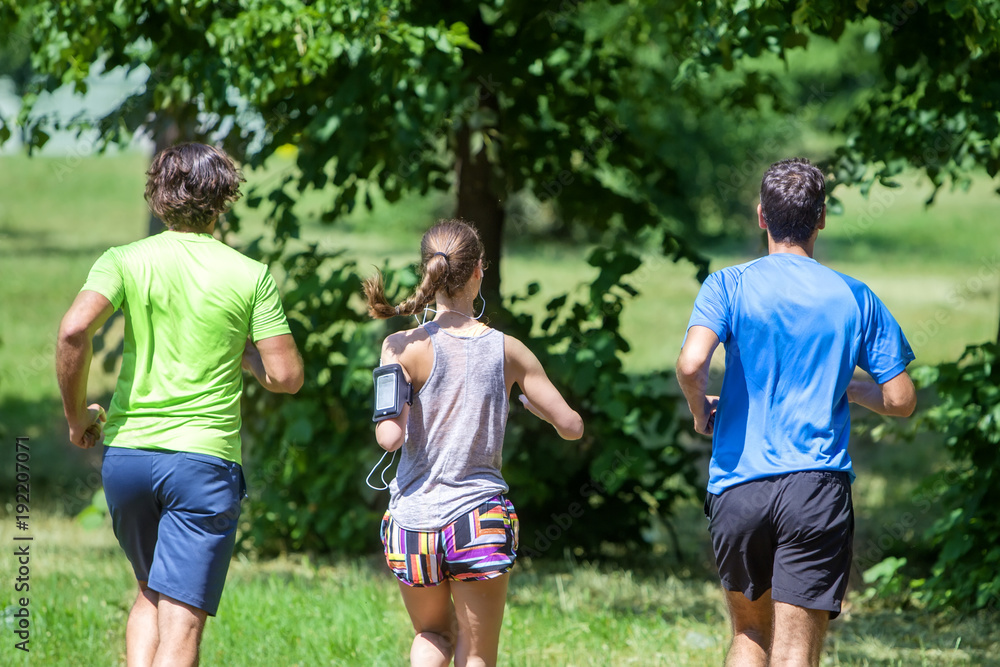 Woman and two young men running in the park Woman and two young men running in the park