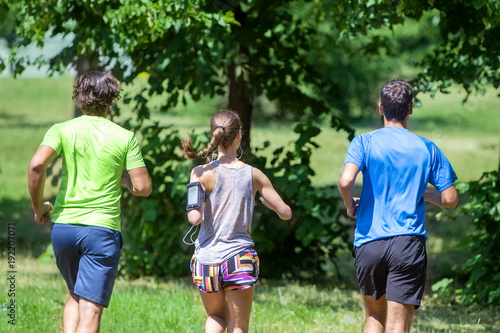 Woman and two young men running in the park