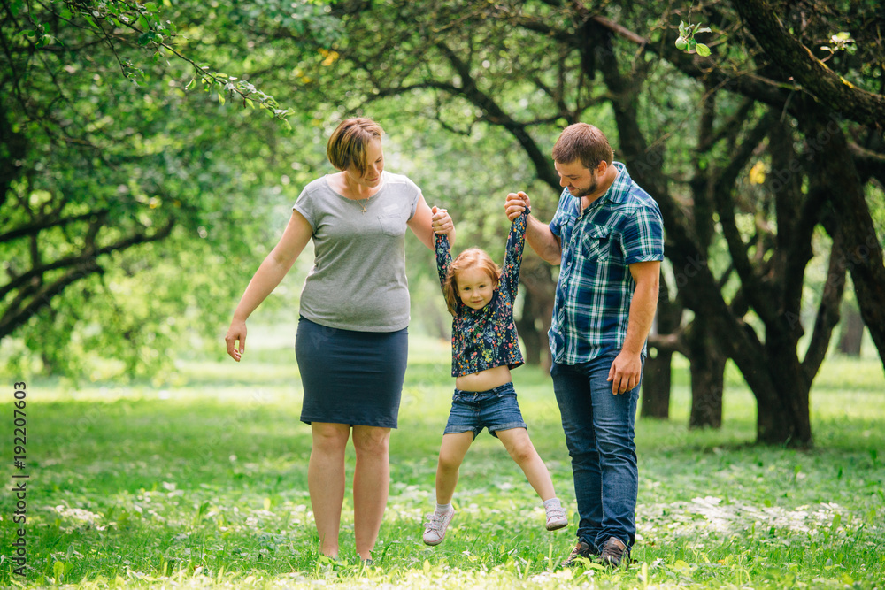 Cute young happy family having fun in the park. Little girl with parents outdoors. Mother father and daughter.