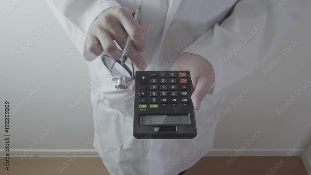 Healthcare costs and fees concept.Hand of smart doctor used a calculator for medical costs in modern hospital Healthcare costs and fees concept.Hand of smart doctor used a calculator for medical costs in modern hospital