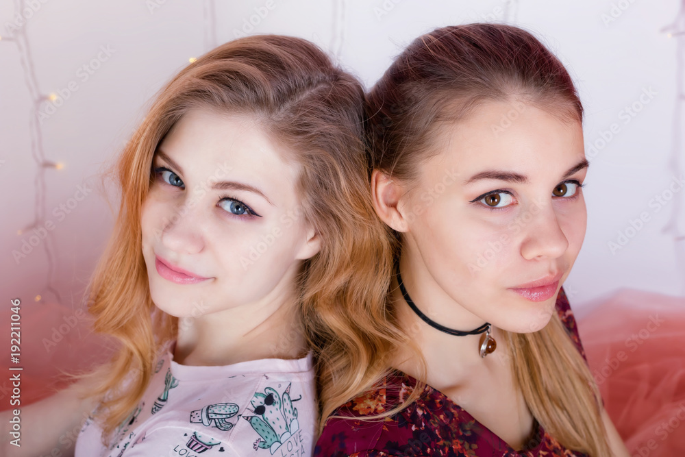 portrait of two pretty girls sitting in a pose back to back portrait of two pretty girls sitting in a pose back to back
