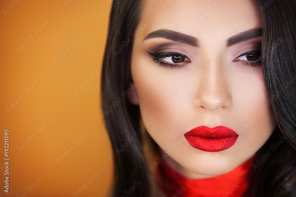 a beautiful girl with sensual bright red lips on an orange background, a red ribbon on her throat does not leave anyone indifferent, everyone looking into her brown eyes. a beautiful girl with sensual bright red lips on an orange background, a red ribbon on her throat does not leave anyone indifferent, everyone looking into her brown eyes.
