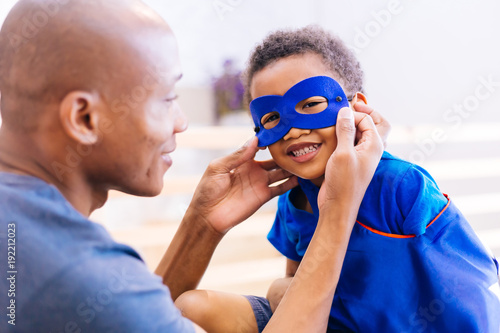 Happy smiling African American son being supported and helped by supportive father for little adventure and protection. photo