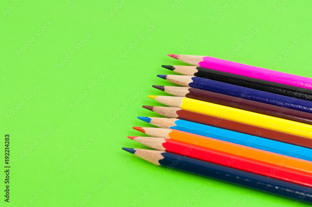 Row of colorful wooden pencils on background of green paper Row of colorful wooden pencils on background of green paper