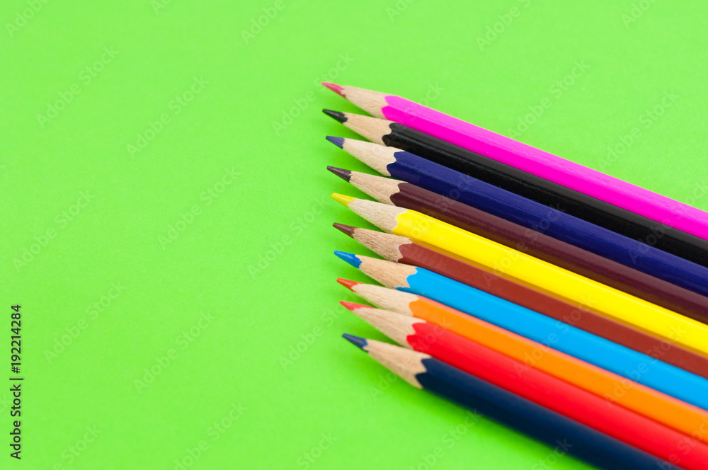 Row of colorful wooden pencils on background of green paper Row of colorful wooden pencils on background of green paper