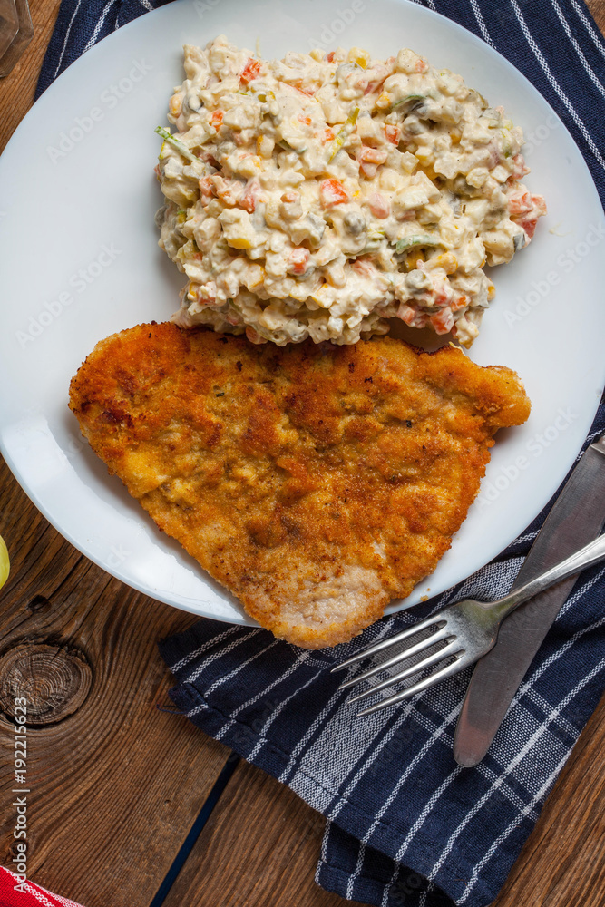 Fried pork chop in breadcrumbs, served with vegetable salad. Fried pork chop in breadcrumbs, served with vegetable salad.