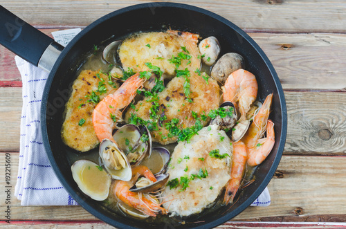 Hake with prawns and clams in frying pan.