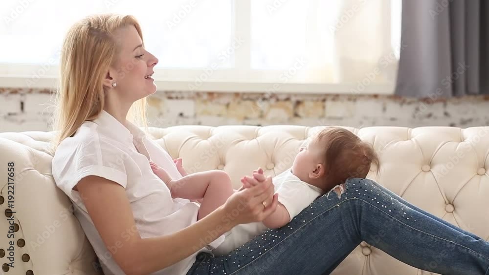 Young mother holding her newborn kid. Happy mom nursing baby. Woman and new born girl together in a white bedroom at home. Mother breast feeding baby. Family lifestyle Young mother holding her newborn kid. Happy mom nursing baby. Woman and new born girl together in a white bedroom at home. Mother breast feeding baby. Family lifestyle