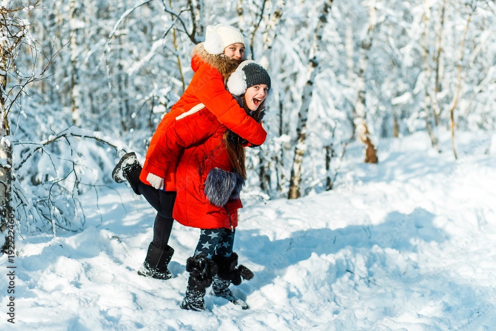 Beautiful teenage girls having fun outside in a wood with snow in winter on a wonderful frosty sunny day. Friendship and active life consept Beautiful teenage girls having fun outside in a wood with snow in winter on a wonderful frosty sunny day. Friendship and active life consept