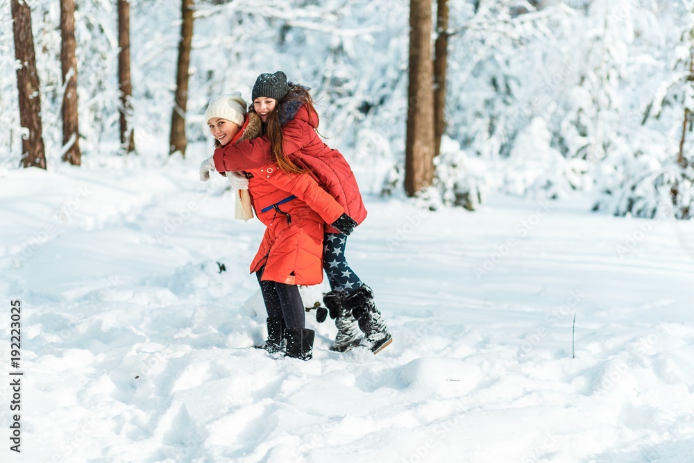 Beautiful teenage girls having fun outside in a wood with snow in winter on a wonderful frosty sunny day. Friendship and active life consept Beautiful teenage girls having fun outside in a wood with snow in winter on a wonderful frosty sunny day. Friendship and active life consept