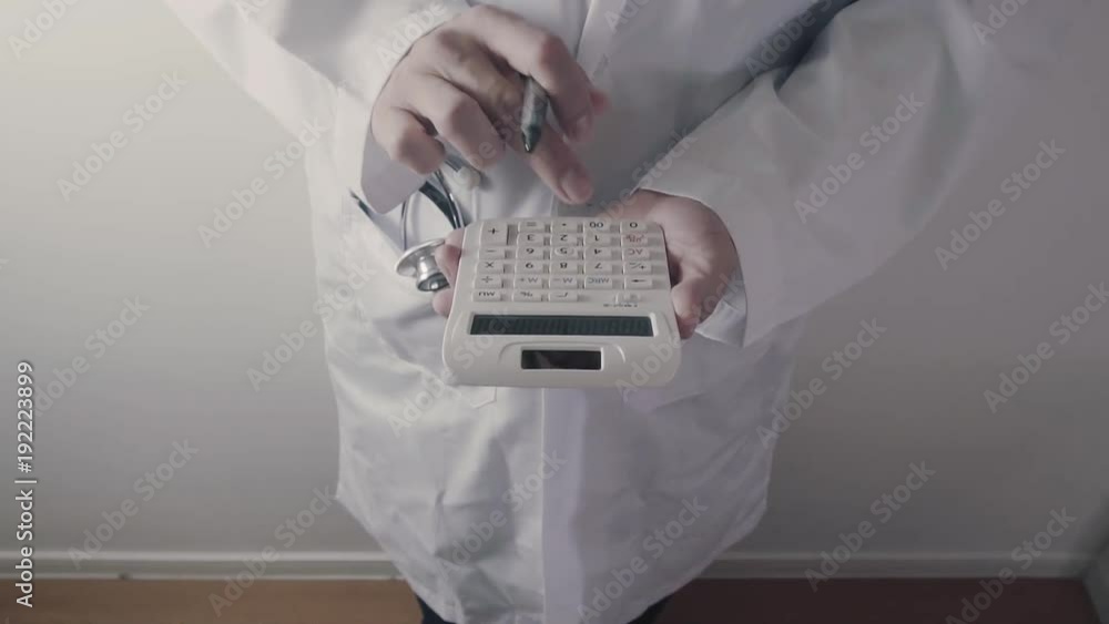 Healthcare costs and fees concept.Hand of smart doctor used a calculator for medical costs in modern hospital Healthcare costs and fees concept.Hand of smart doctor used a calculator for medical costs in modern hospital