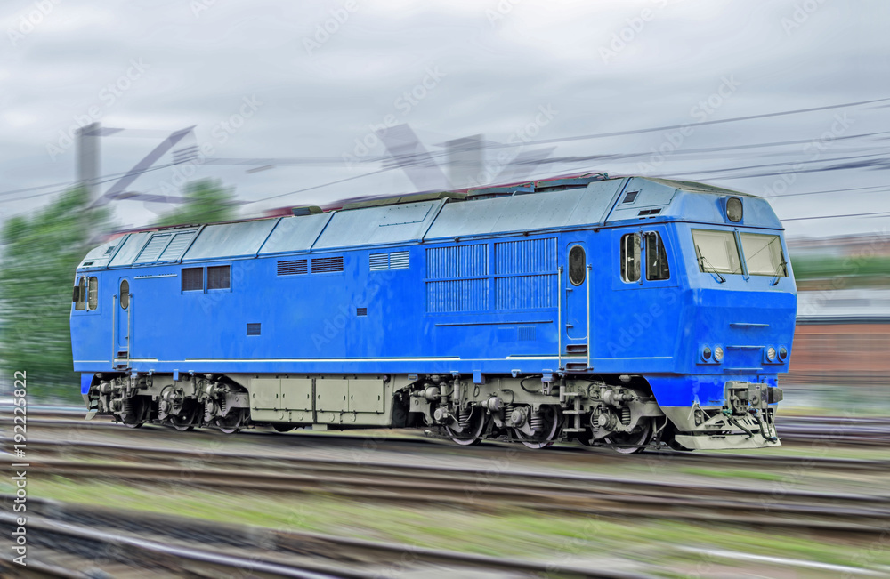 Blue locomotive diesel train at high speed rides by rail.