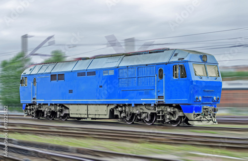 Blue locomotive diesel train at high speed rides by rail.
