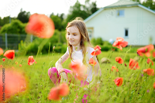 Adorable little girl admiring the poppy flowers in a garden