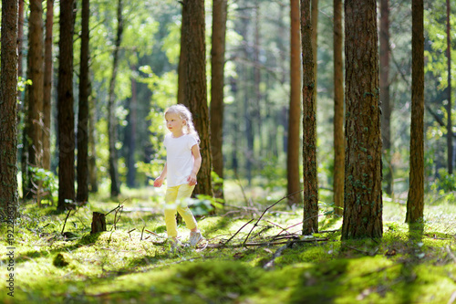 Cute little girl having fun during forest hike on beautiful summer day