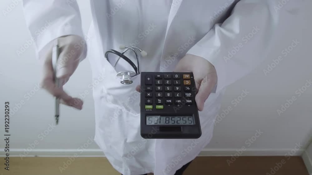 Healthcare costs and fees concept.Hand of smart doctor used a calculator for medical costs in modern hospital Healthcare costs and fees concept.Hand of smart doctor used a calculator for medical costs in modern hospital