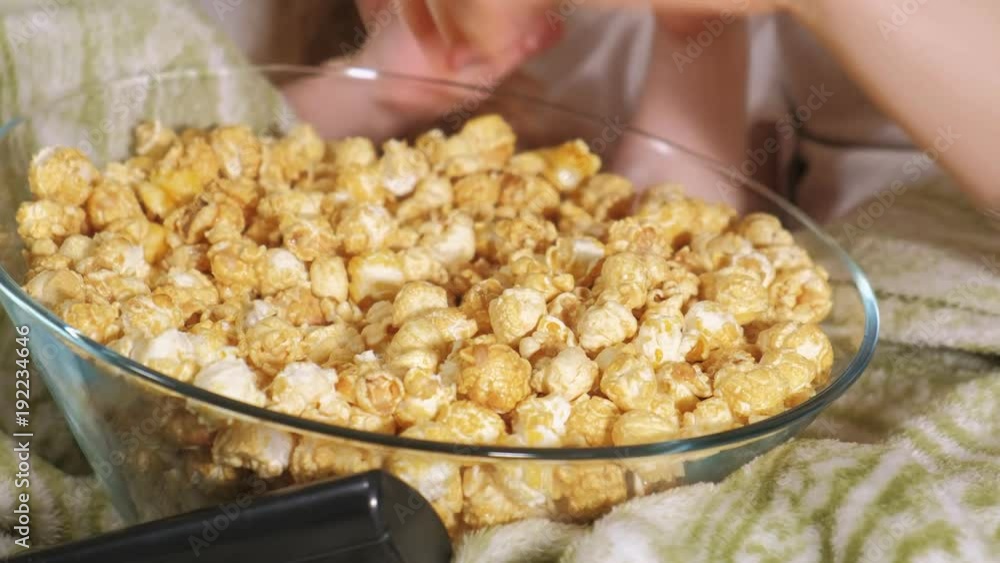 Happy loving family. Mother and her daughter child girl are eating popcorn on the bed in the room. front of the TV Happy loving family. Mother and her daughter child girl are eating popcorn on the bed in the room. front of the TV