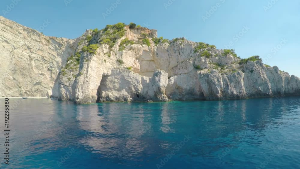 Island in the sea with clear blue seawater around seen from a sailing boat in the summer Island in the sea with clear blue seawater around seen from a sailing boat in the summer
