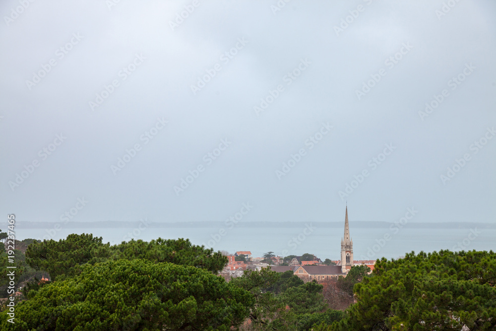 Aerial view of Arcachon, France, during a storm on a rainy day, with Notre Dame basilica in front. Located in Arcachon bay, the city is one of most touristic spots of the Atlantic coast in France