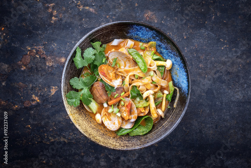 Traditional Thai kaeng phet red curry with clams and vegetable as top view on a plate