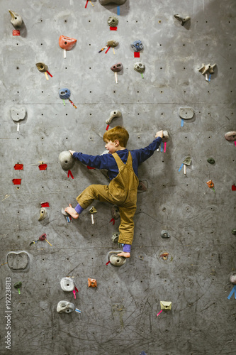 Rear view of boy climbing wall at health club photo