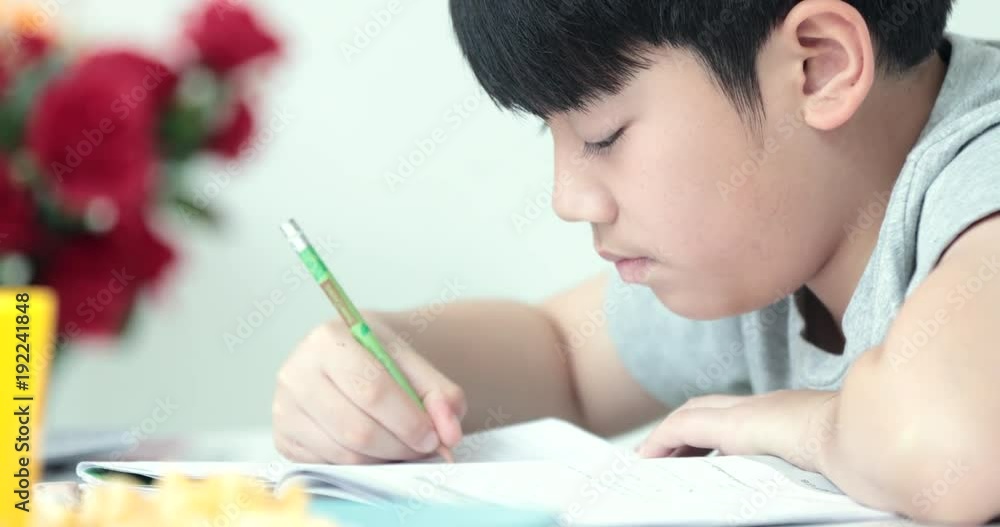 Happy asian cute boy hand holding pencil and writing your homework at home.