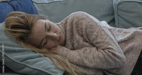Young sleepy woman falling down on sofa at home.