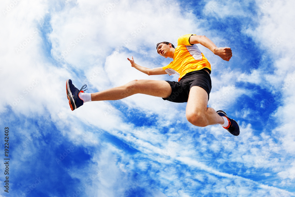 Sportsman remains in air while jumping against sky