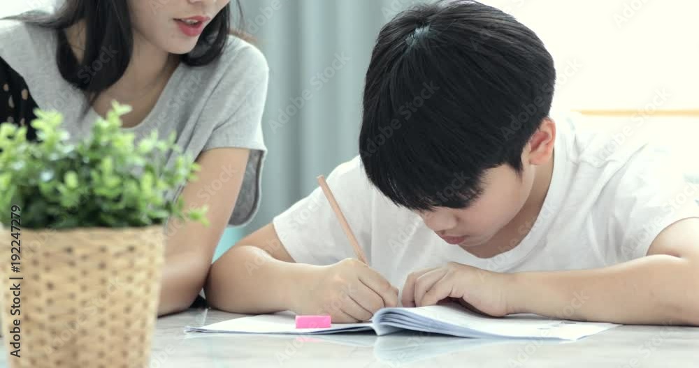 Asian Mom is helping her son to do homework of the school at home. Asian Mom is helping her son to do homework of the school at home.