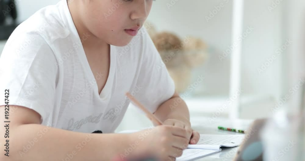 Happy asian cute boy hand holding pencil and writing your homework at home. Happy asian cute boy hand holding pencil and writing your homework at home.