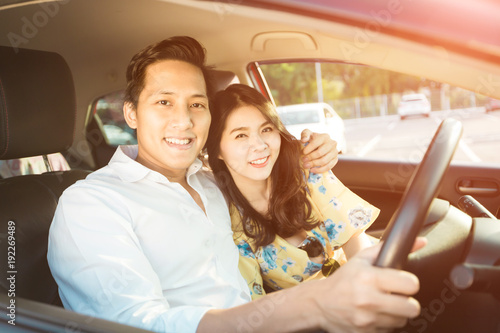 Young couple sitting on the front passenger seats and smiling , man driving a red car. © chompoo