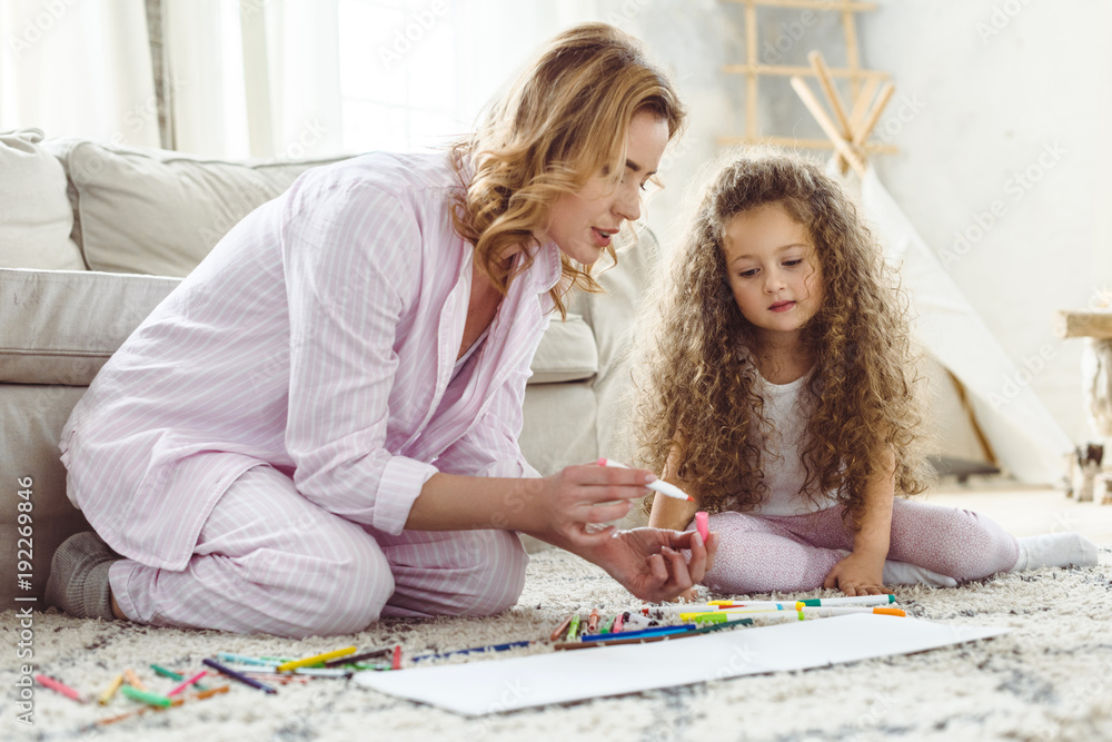 curly daughter and mother drawing with markers in album curly daughter and mother drawing with markers in album
