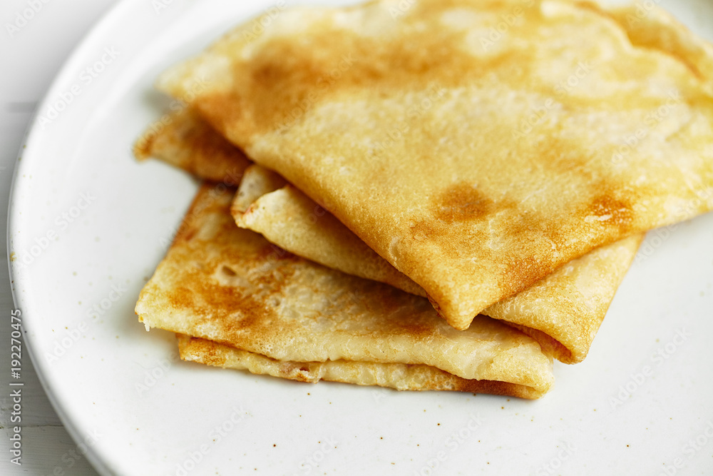 Macro shot of french crepes stacked in white plate