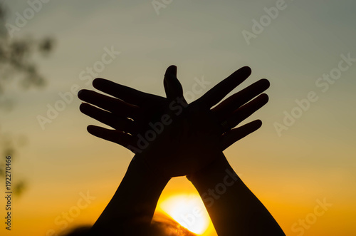 The silhouette of a girl is holding a symbolic hand in a beautiful sunset.