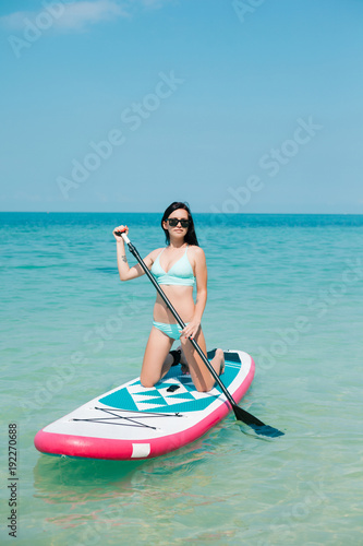 attractive girl on stand up paddle board on sea