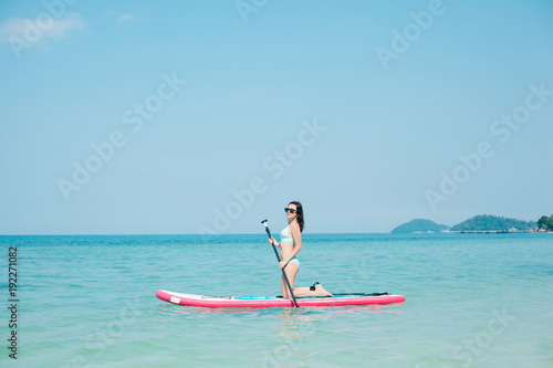 young girl on stand up paddle board on sea at tropical resort