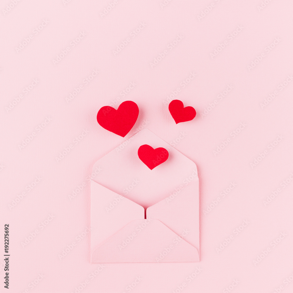 Valentines day background of pink paper envelop and stream soar red small hearts on pink paper background.