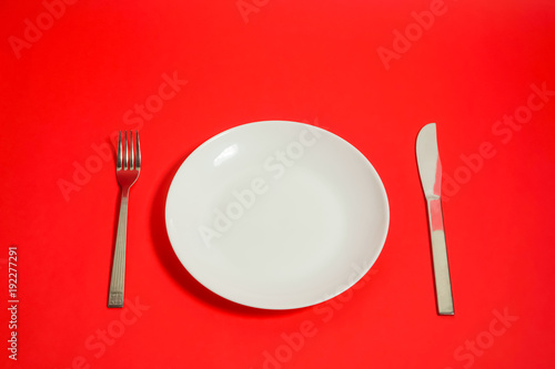 a white dish and a fork and a knife   白いお皿とナイフとフォーク　赤色背景