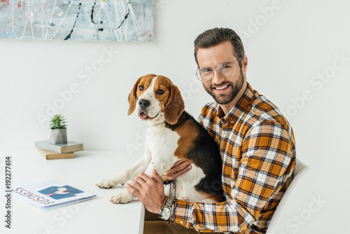 businessman holding cute beagle and looking at camera