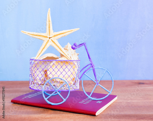 Travel concept, toy bicycle and sea shells on the wooden table.