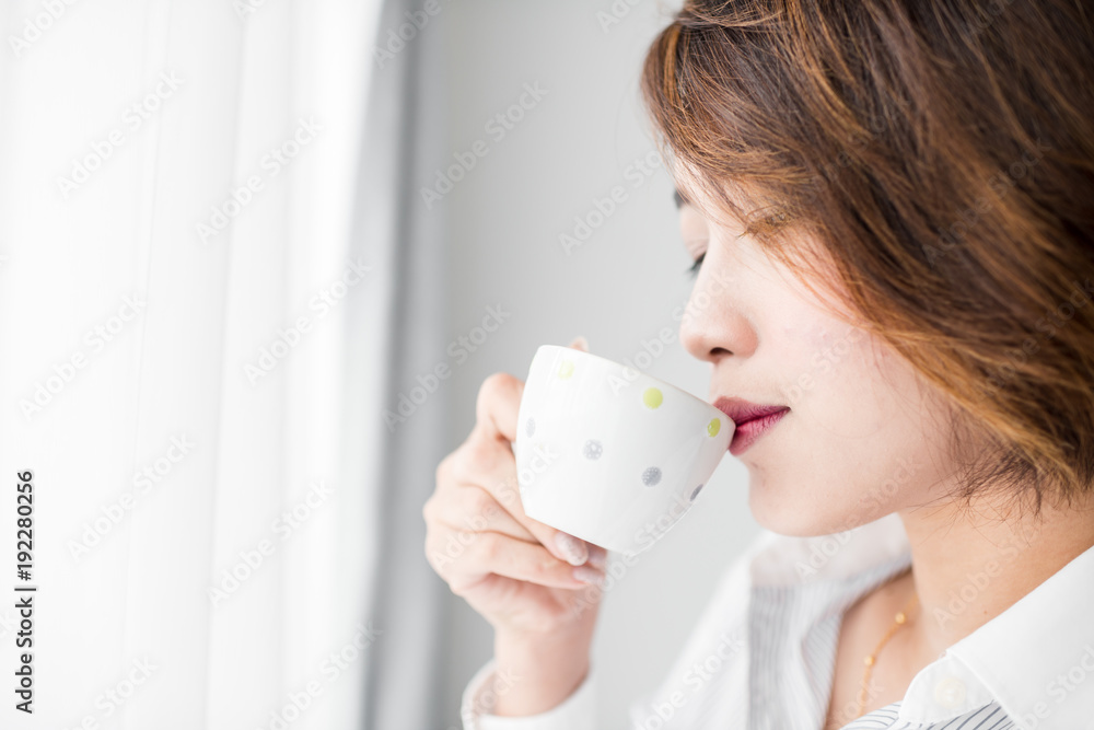 Happy young businesswoman drinking tea while sitting in chair at home Happy young businesswoman drinking tea while sitting in chair at home
