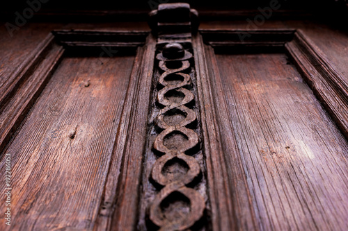 Vintage background. Elements of an old carved wooden door decorated with voluminous carved wooden elements imitating the weaving. A vintage concept of old antiques. Varnished old mahogany