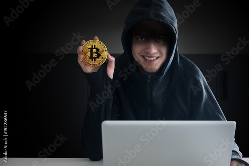 Hacker showing a coin of virtual currency.