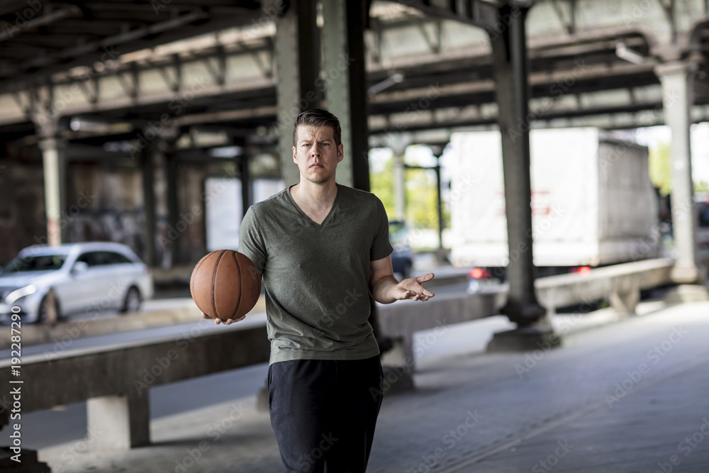 Man With a Basketball Standing Under a City Bridge Man With a Basketball Standing Under a City Bridge