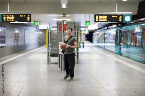 Man With a Basketball Standing at a Subway Station Platform
