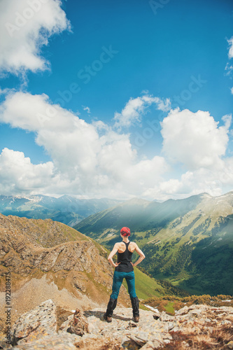 Woman hiker standing on the top of mountain. Back pose