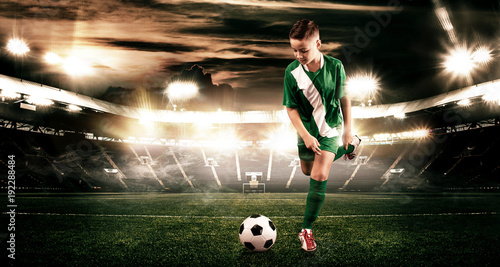 Kid - soccer player. Boy forward in football sportswear on stadium with ball. Sport concept.