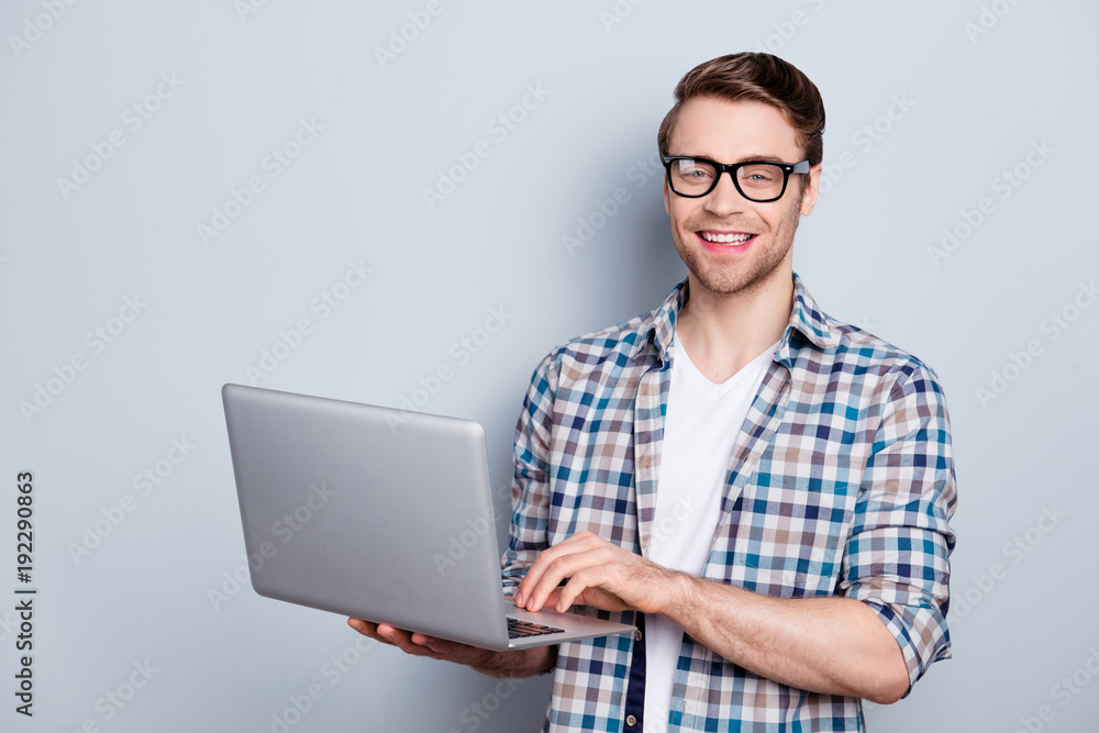 Portrait of bearded, cheerful, brunet guy holding open laptop, looking at camera, searching information through wifi internet, standing over grey background Portrait of bearded, cheerful, brunet guy holding open laptop, looking at camera, searching information through wifi internet, standing over grey background